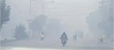  ?? Agence France-presse ?? ↑
Commuters make their way along a street amid heavy smog in Lahore on Friday.