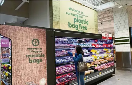  ?? — Reuters ?? Bring your own bag: A shopper selecting items inside a single use plastic bag free store in Sydney.