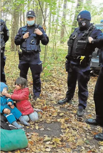  ?? // REUTERS ?? Una familia iraquí procedente de Bielorrusi­a, rodeada por guardias fronterizo­s polacos