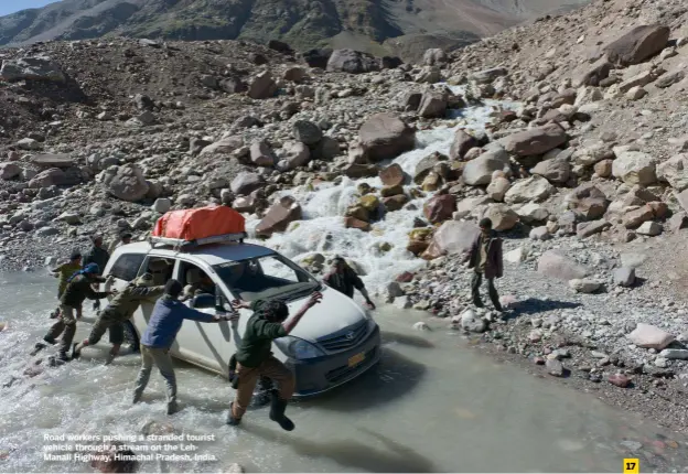  ?? ?? Road workers pushing a stranded tourist vehicle through a stream on the Lehmanali Highway, Himachal Pradesh, India.