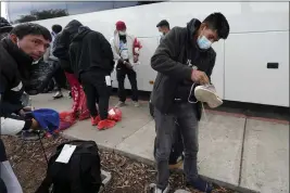  ?? GREGORY BULL — THE ASSOCIATED PRESS ?? Migrants unload their items off a bus as they arrive at a bus stop after leaving a processing facility Friday in San Diego. Hundreds of migrants were dropped off Friday at a sidewalk bus stop amid office parks in San Diego with notices to appear in immigratio­n court after local government funding for a reception center ran out of money sooner than expected.