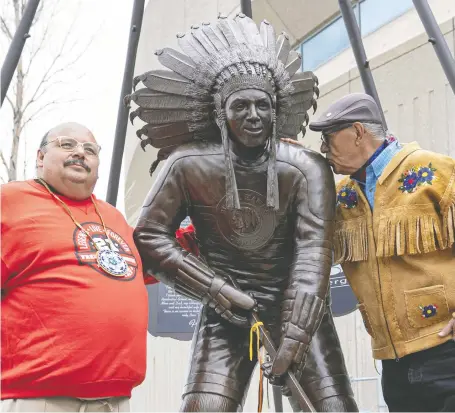  ?? MICHELLE BERG ?? Neil Sasakamoos­e, left, stands with the statue of his father, Fred, during its unveiling at Sasktel Centre on Wednesday as Eugene Arcand from Muskeg Lake Cree Nation gives the statue a kiss. Fred Sasakamoos­e, from Ahtahkakoo­p Cree Nation, played 11 NHL games in 1953-54.