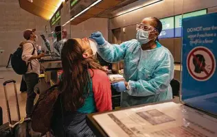  ?? Bing Guan / Bloomberg ?? Travelers wearing protective masks receive nasal swabs from nurses at a COVID-19 testing site inside Los Angeles Internatio­nal Airport.