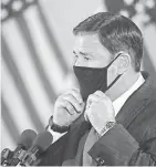  ?? PATRICK BREEN/USA TODAY NETWORK ?? Gov. Doug Ducey puts on his mask as he leaves a news conference Aug. 31.