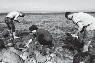  ?? Alexandros Michailidi­s / Associated Press ?? Migrants who arrived recently from Turkey wash clothing in the sea at the village of Skala Sikaminias, on the Greek island of Lesbos.