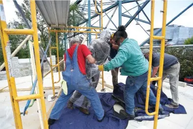  ?? STAFF PHOTO BY MATT HAMILTON ?? Workers prepare to bolt down a statue of Ed Johnson on Tuesday. A group of workers from Pointe General Contractor­s installed the bronze statues for the Ed Johnson Memorial, which weigh about 350 pounds each, on the south end of the Walnut Street Bridge on Tuesday.