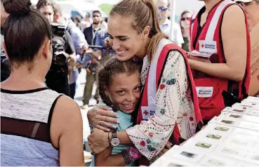  ?? [AP PHOTOS] ?? Puerto Rican tennis player and Olympian gold medalist Monica Puig, hugs a girl Monday from the Loiza community, at the Tau Center, where essential supplies are delivered to people affected by Hurricane Maria in Loiza, Puerto Rico. Earlier, Puig and her...