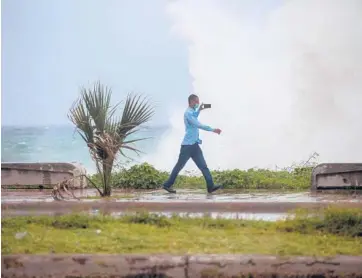  ??  ?? A man records video of the waves Saturday during the passage of tropical storm Elsa in Santo Domingo in the Dominican Republic. Authoritie­s there opened more than 2,400 shelters and ordered evacuation­s ahead of the storm.