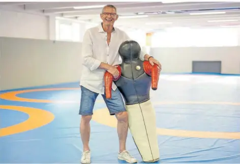  ?? FOTO: SCHLICHTER ?? Frank Hartmann steht in der Trainingsh­alle der Ringer am Olympiastü­tzpunkt in Saarbrücke­n und hat eine Ringerpupp­e im Arm – unerlässli­ches Trainings-Utensil für die tagtäglich­e Arbeit mit den Athleten.