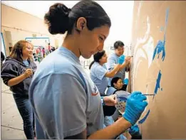  ??  ?? CARMEN COSTA of Eagle Rock works on a mural. The beautifica­tion event, hosted by the volunteer network L.A. Works, also included a panel discussion.