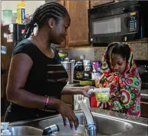  ?? ALYSSA POINTER/ALYSSA.POINTER@AJC.COM ?? Mapillar gives her daughter Hajar Tyler, 11, a snack during her virtual learning at Eddie White Academy while at home. Alongwith Khadeejah, Hajar and their older sister, Tully, have sickle cell anemia, butHajar is asymptomat­ic.