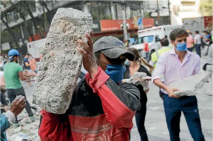  ?? PHOTO: REUTERS ?? People carry debris outside a collapsed building after an earthquake in Mexico City yesterday. Dozens of buildings were reduced to rubble in the magnitude 7.1 shake.