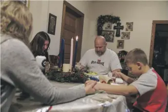  ?? ?? Jason Wolter prays at the dinner table with his wife, Tracy (from left), daughter Bella, 17, and son Zeb, 9, at their home in Benson, Minn.