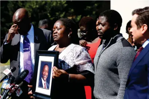  ?? ?? Caro l ine Ouko ho l ds a portrait of her son I rvo Otieno at the Dinwiddie Courthouse in Virginia (AP)