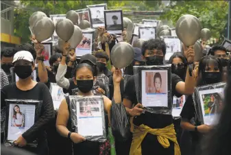  ?? Associated Press ?? Coup protesters clad in black hold pictures of those who have been killed during a memorial march against the military junta in Yangon. At least 570 protesters and bystanders have died.