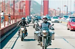  ?? — AP photos ?? In this photo provided by Alisa Clickenger, Clickenger leads a group of women riders over the Golden Gate Bridge in San Francisco at the end of a cross-country trip to honor two sisters from Brooklyn, NY, who made a similar ride in 1916.