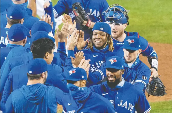  ?? GREGORY FISHER / USA TODAY SPORTS ?? The Blue Jays celebrate after clinching a playoff spot following a victory over the New York Yankees at Sahlen Field on Thursday.