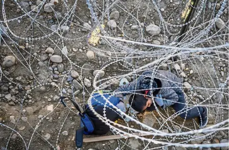  ??  ?? Treacherou­s journey: Kevin Andres, a Mexican migrant child from Oaxaca, crawling to get his backpack from the barbed wire after jumping the border fence to get into the US side, to San Diego, from Tijuana, Mexico. — AP