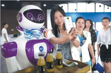  ?? LI ZHANJUN / FOR CHINA DAILY ?? A visitor takes a selfie with a service robot at a makerspace in the Guangzhou Developmen­t District.