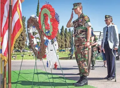  ?? PHOTOS BY TOM TINGLE/THE REPUBLIC ?? Members of the East Valley Young Marine Color Guard salute as wreaths are presented at Monday’s Memorial Day Remembranc­e at Mesa Memorial Cemetery.