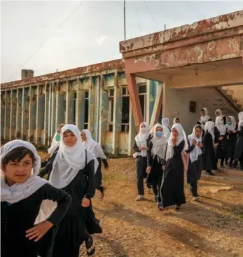  ??  ?? Gadis-gadis etnis minoritas Uzbek berjalan keluar dari Sekolah Menengah Marshal Dostum di kota barat laut Shibirghan, Provinsi Jowzjan. Keluarga dari lebih dari dua puluh siswa, pindah ke ibu kota provinsi ini setelah Taliban menguasai distrik-distrik selatan provinsi, dan kembali melarang pendidikan perempuan pada 2018.