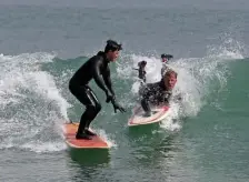  ?? STuART CAHiLL / HeRALd sTAFF ?? NO SUCH THING AS TOO CLOSE IF YOU’RE VACCINATED: Two people nearly collide as surfers came out in droves and the temps closed in on 70 on Saturday in Hull, but that’s OK if you’re vaccinated.