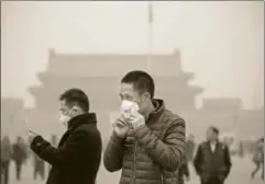  ?? GETTY IMAGES ?? A tourist puts on a face mask at Tiananmen Square in Beijing, China