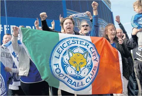  ?? AFP ?? Leicester City fans hold an Italy’s flag with the club’s crest as they celebrate the team’s triumph outside the King Power Stadium.