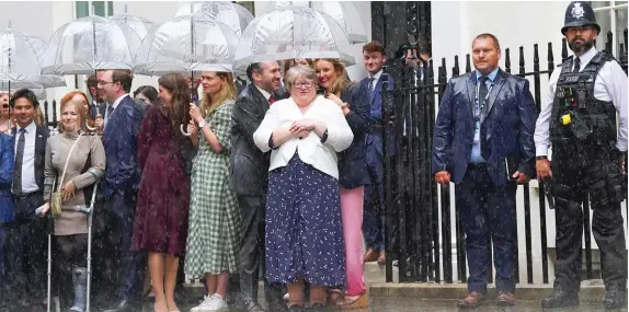  ?? ?? Brolly good show! The new Deputy Prime Minister Therese Coffey, centre, huddles with the rest of Team Truss outside No 10 yesterday