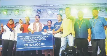  ??  ?? Nanta (fourth left) presents a grant under Program Peningkata­n Pendapatan Risda for rubber planting to a representa­tive.