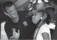  ?? Bob Owen / Staff photograph­er ?? Nalani Washington, right, of Houston, tries on a firefighte­r’s helmet with Kerrville Fire Department member Lane Rhea on Wednesday during Camp David, an annual pediatric burn camp.