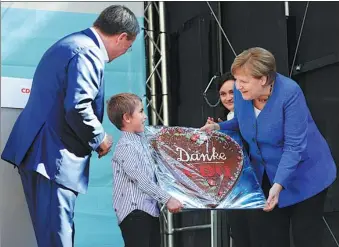  ?? WOLFGANG RATTAY / REUTERS ?? German Chancellor Angela Merkel receives a traditiona­l cake reading ‘thank you’ as she attends a rally in Aachen, western Germany, on Saturday.