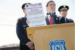  ?? SPENCER PLATT/GETTY IMAGES ?? Suffolk County Police Commission­er Timothy Sini holds up a notice offering a reward for informatio­n that leads to an arrest in the case.