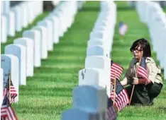  ?? ?? LOS ANGELES: A scout places a flag beside gravestone­s at the Los Angeles National Cemetery on Saturday ahead of Memorial Day. —AFP