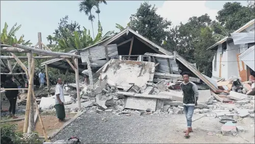  ??  ?? Villagers walk near destroyed homes in an area affected by the early morning earthquake at Sajang village, Sembalun, East Lombok, Indonesia.