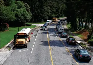  ?? HYOSUB SHIN / HSHIN@AJC.COM ?? A Fulton County school bus stops on Powers Ferry Road in Sandy Springs on Wednesday. A phrase added to a 15-page bill late in the Georgia legislativ­e session has caused panic among officials responsibl­e for getting children to and from school safely.