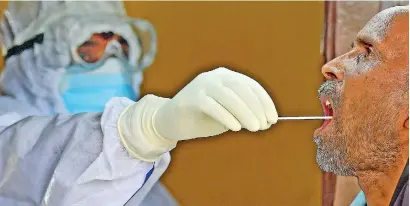  ??  ?? A health official takes a swab sample from a man to test for the COVID-19 coronaviru­s at a testing point in Allahabad