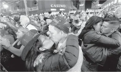  ?? STEVE MARCUS/LASVEGAS SUN 2018 ?? At center-left, newlyweds Alison and Kenny Finchum, of Tulsa, Oklahoma, kiss during a New Year’s party at the Fremont Street Experience in Las Vegas. Plans for a 14,000-person street party are facing pushback from state and local officials.