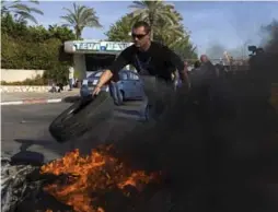  ?? TSAFRIR ABAYOV/THE ASSOCIATED PRESS ?? Some workers burned tires outside a Teva plant in Ashdod on Dec. 17 to protest massive cuts in the company’s workforce.