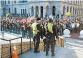  ?? ROBERTO SCHMIDT/GETTY-AFP ?? Virginia State Police keep watch on gun-rights advocates Monday in front of the state Capitol in Richmond.