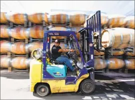  ??  ?? SAMUEL GARCIA transports wine barrels at Alexander Valley Vineyards last week. By contrast, wines from Australia and Chile are taxed just 26% in China.