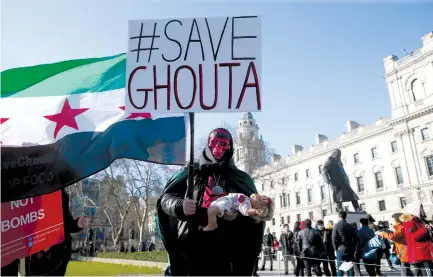  ?? (Paul Hackett/Reuters) ?? A DEMONSTRAT­OR holds a flag and a doll during a Syria solidarity protest outside the Houses of Parliament in London on Saturday.