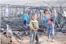  ?? — AFP ?? Syrian refugees check the damage following a fire that ripped through their refugee camp in Lebanon’s eastern Bekaa Valley.