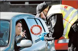  ?? JEAN-FRANCOIS BADIAS/AP ?? A German police officer checks authorizat­ion for a woman to enter from France.