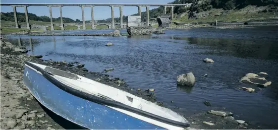  ?? Foto: dpa ?? Trockenhei­t in Galicien: Ein Boot ruht am Ufer des Río Miño, im Hintergrun­d sind die Ruinen des alten Portomarin zu sehen.