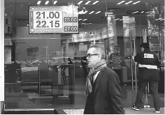  ??  ?? A man walk pass a board displaying the exchange rate of Mexican peso against the US dollar at Mifel bank branch in Mexico City. Mexico’s peso fell to a new low after US President-elect Donald Trump vowed to make the country pay for a huge border wall...