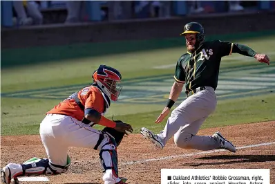  ?? AP Photo/Ashley Landis ?? Oakland Athletics' Robbie Grossman, right, slides into score against Houston Astros catcher Martin Maldonado during the eighth inning Wednesday of Game 3 in the American League Division Series in Los Angeles.