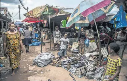  ?? Photo: Khaled Desouki/AFP ?? Life goes on in Gabon: A man sets out his wares on the ground in a market in Francevill­e ahead of the Africa Cup of Nations.