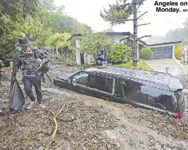  ?? AP ?? Residents evacuate damaged vehicles after storms caused a mudslide in the Beverly Crest area of Los Angeles on Monday.