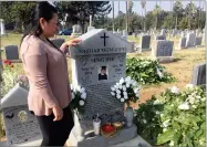  ?? AP PHOTO BY LEWIS GRISWOLD ?? In this Tuesday photo, Youa Her, of Fresno inspects the headstone of her late husband after it was moved back into position at Mountain View Cemetery in Fresno. The manager of the cemetery in central California says he will learn more about Hmong...